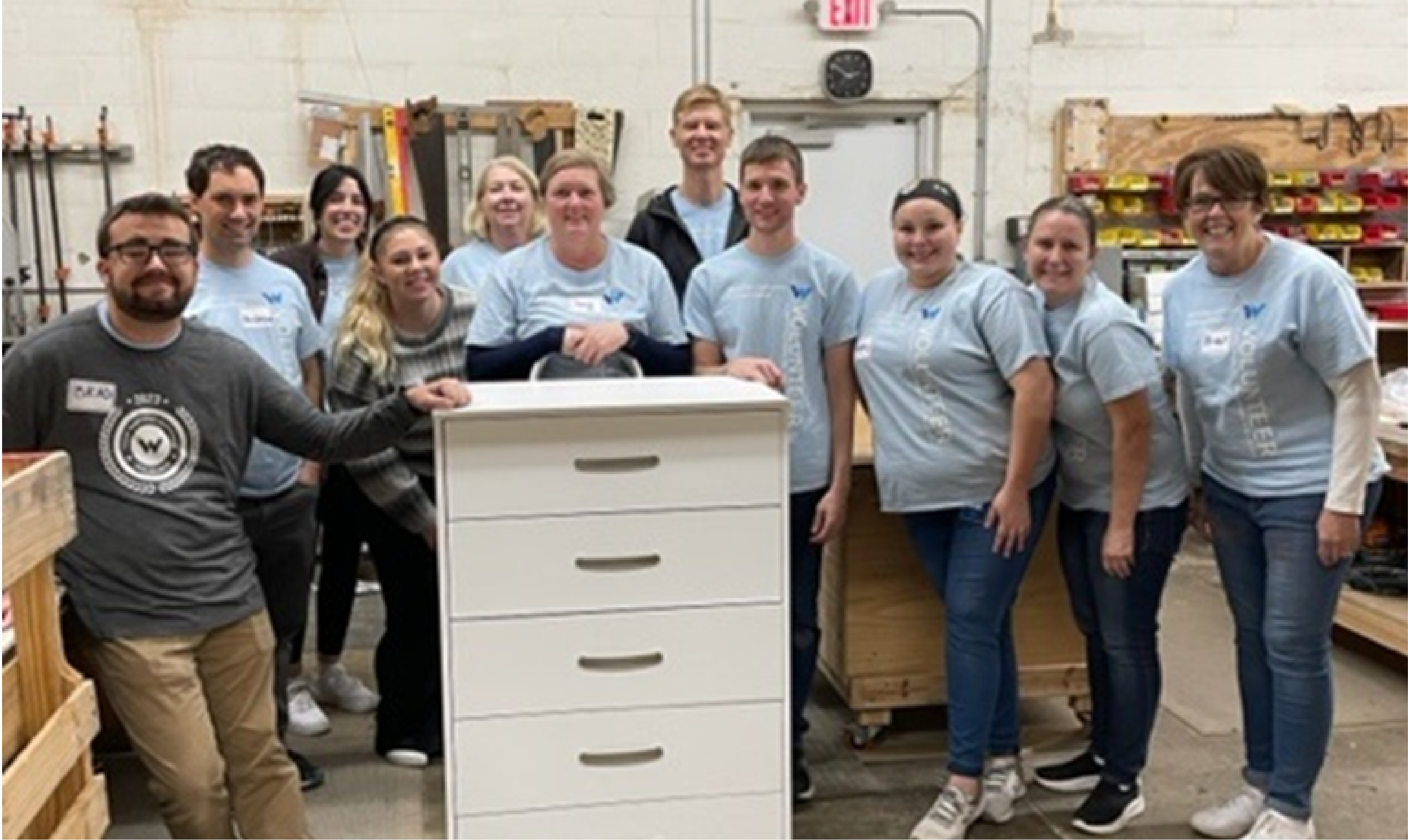Western National employees smiling for the camera behind a dresser they helped assemble for Bridging.