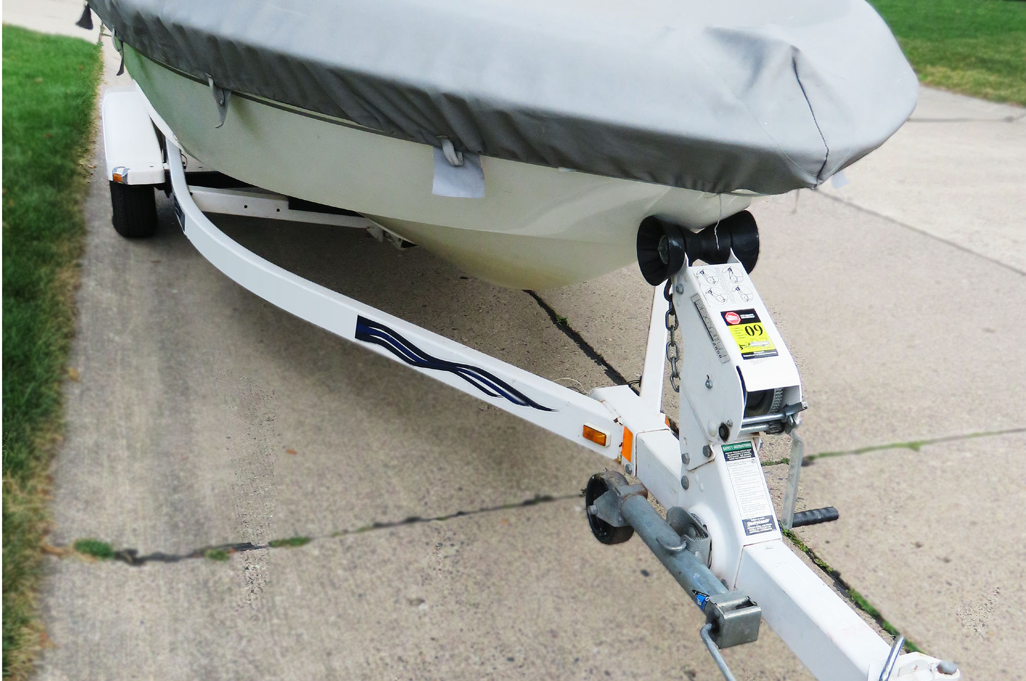 Small speedboat on a trailer being towed on a street.