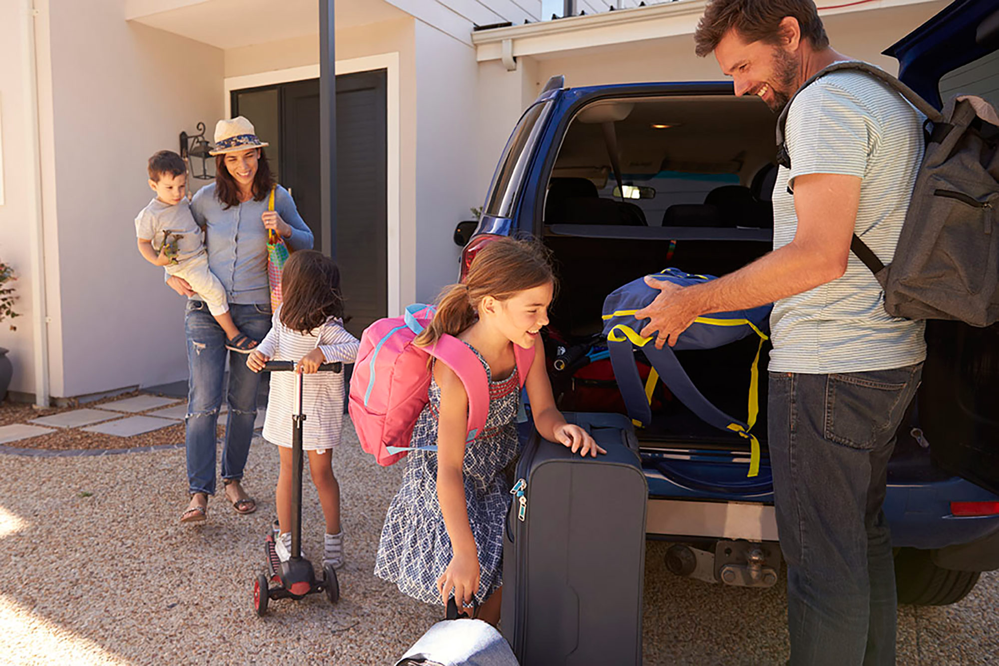 Young family packing suitcases and belongings into a vehicle.