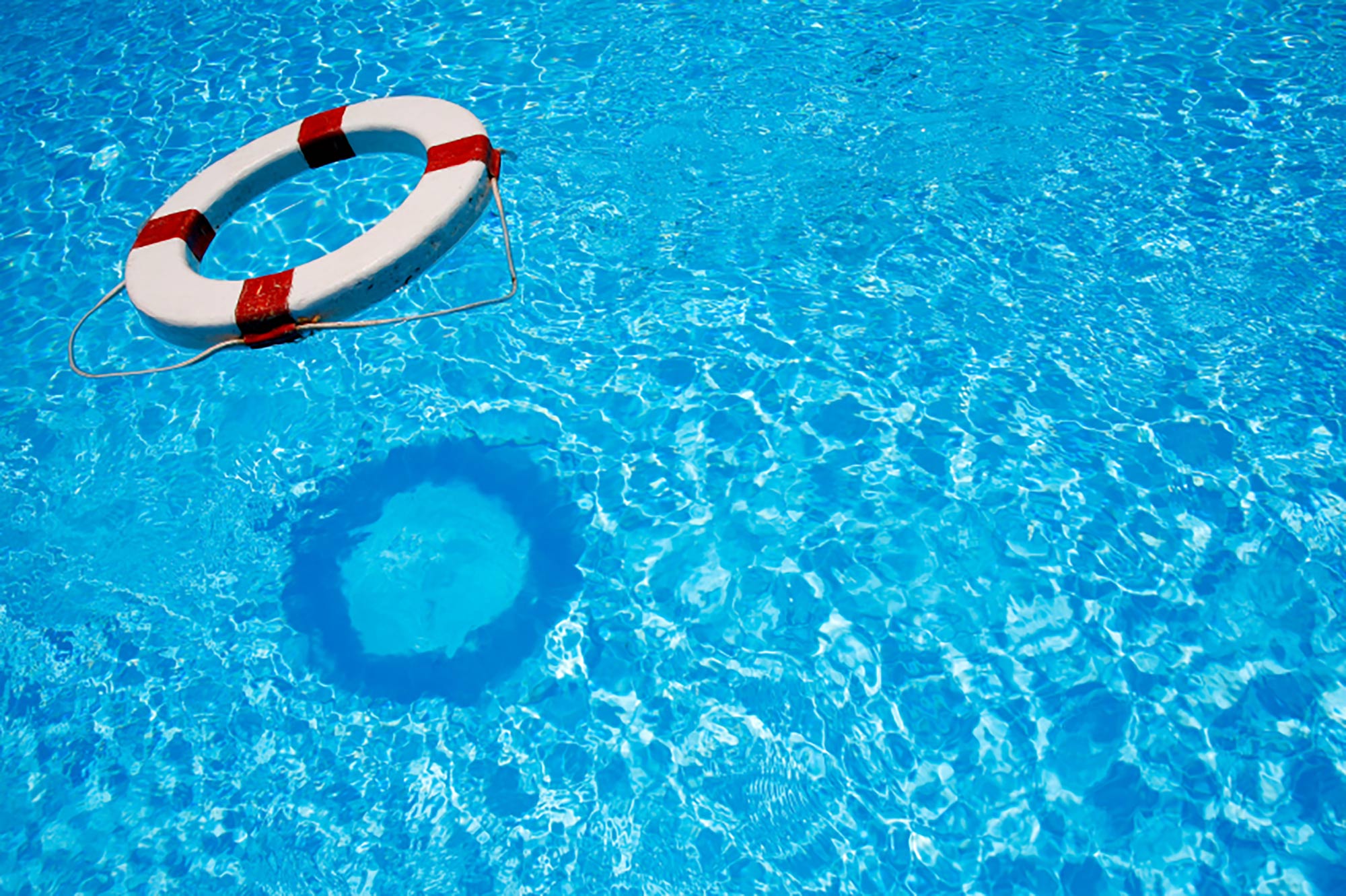 Red and white striped circular life preserver floating in a pool.