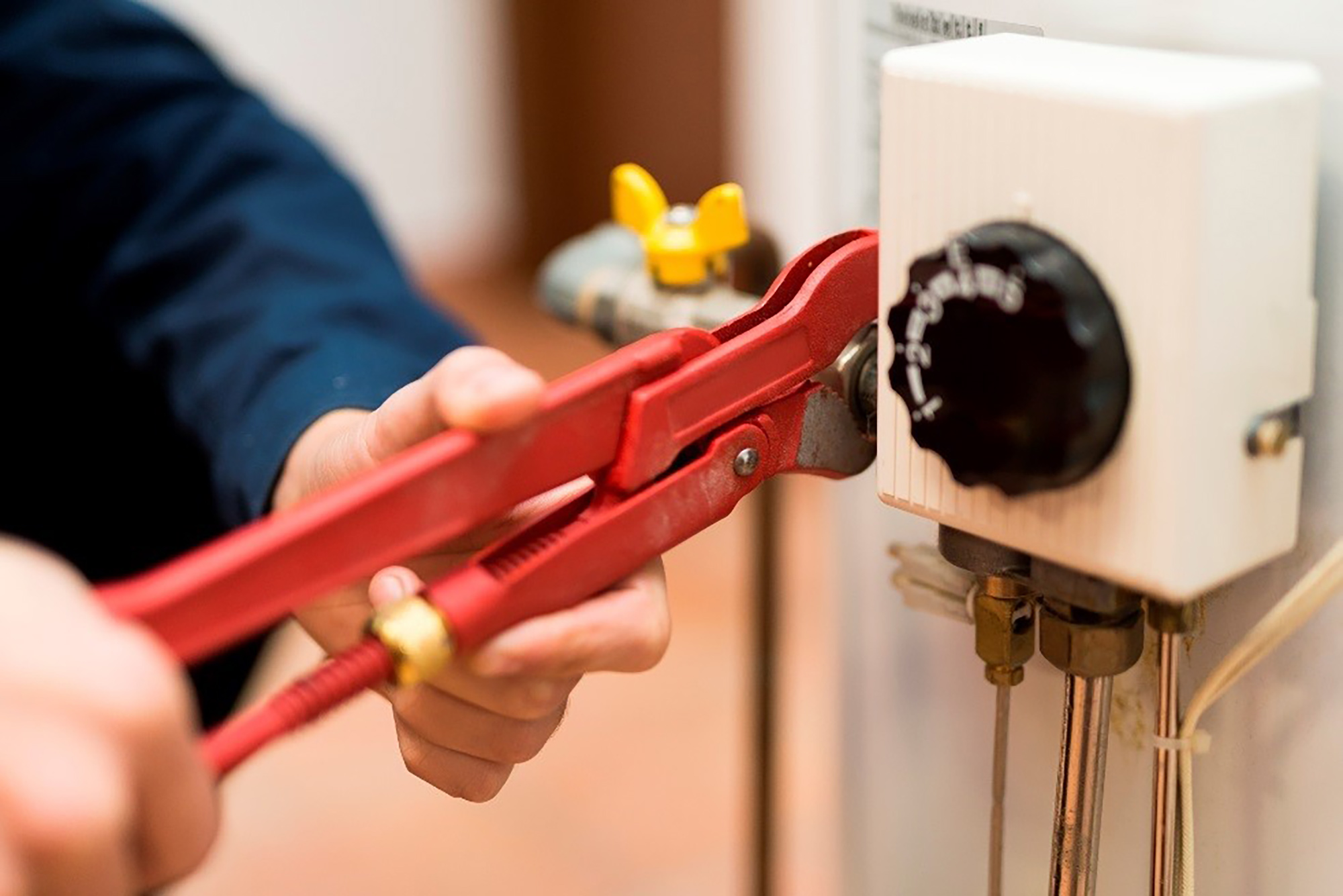 Close-up of person using a wrench to work on a water heater.
