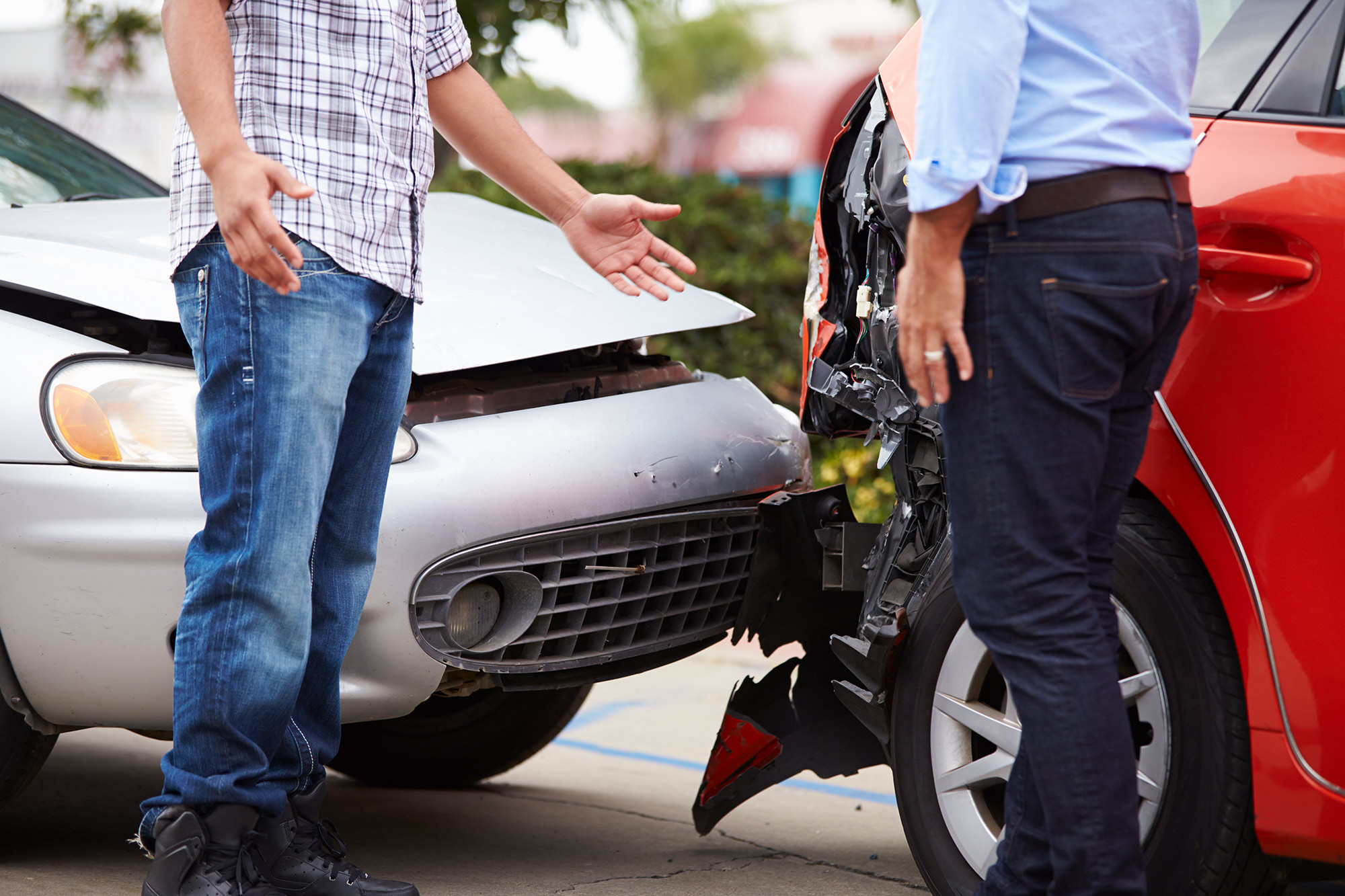Two people standing at the scene of an accident, examining a crash.