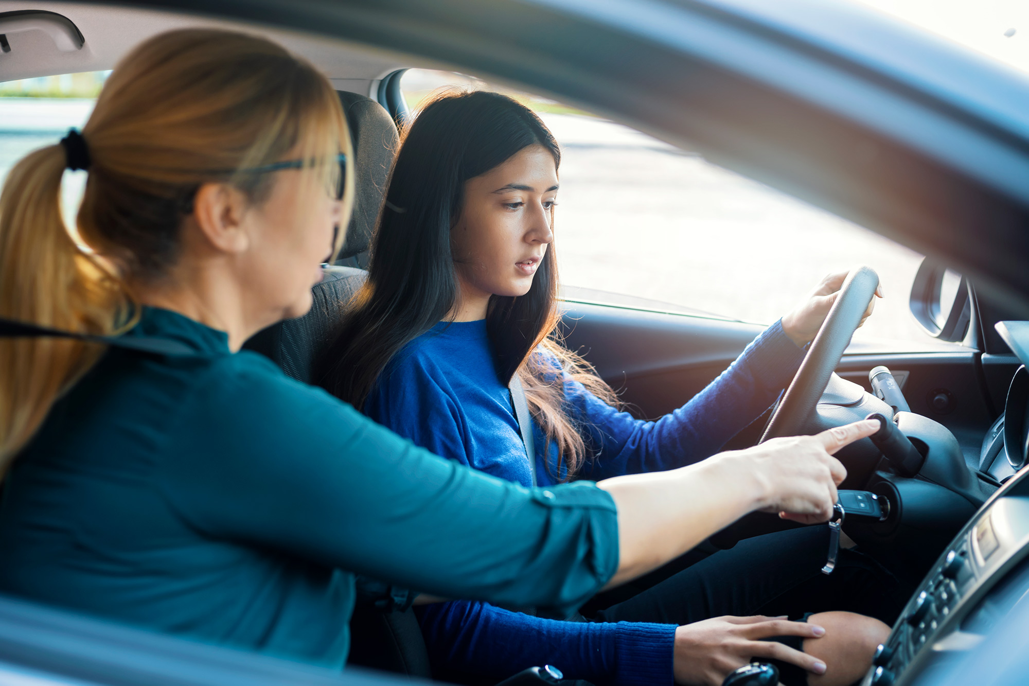 Woman giving daughter driving lesson.