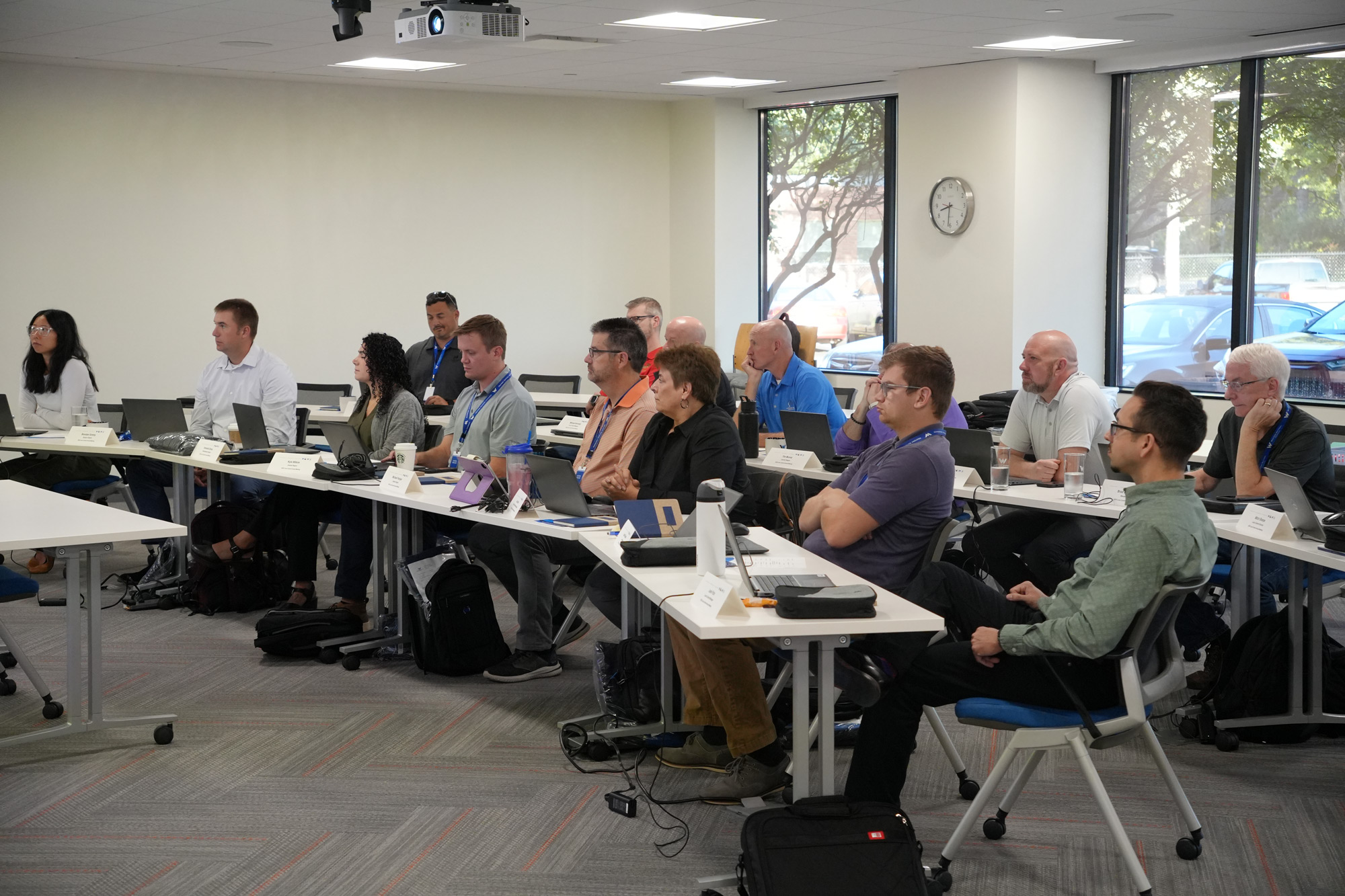 A room full of employees paying attention to a presentation in a large conference room.