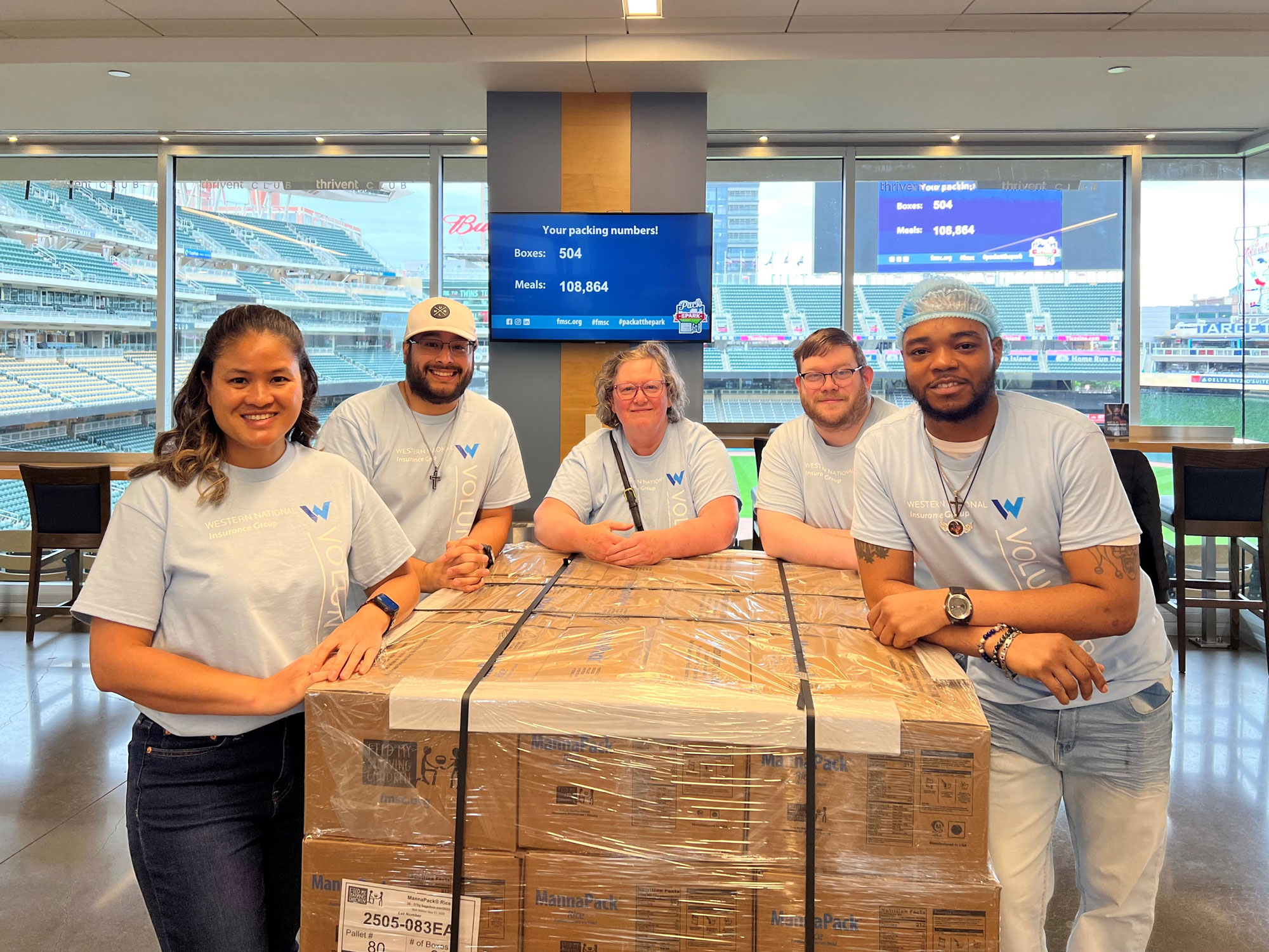 A group of employees smiling at the camera at a Feed My Starving Children volunteer event.