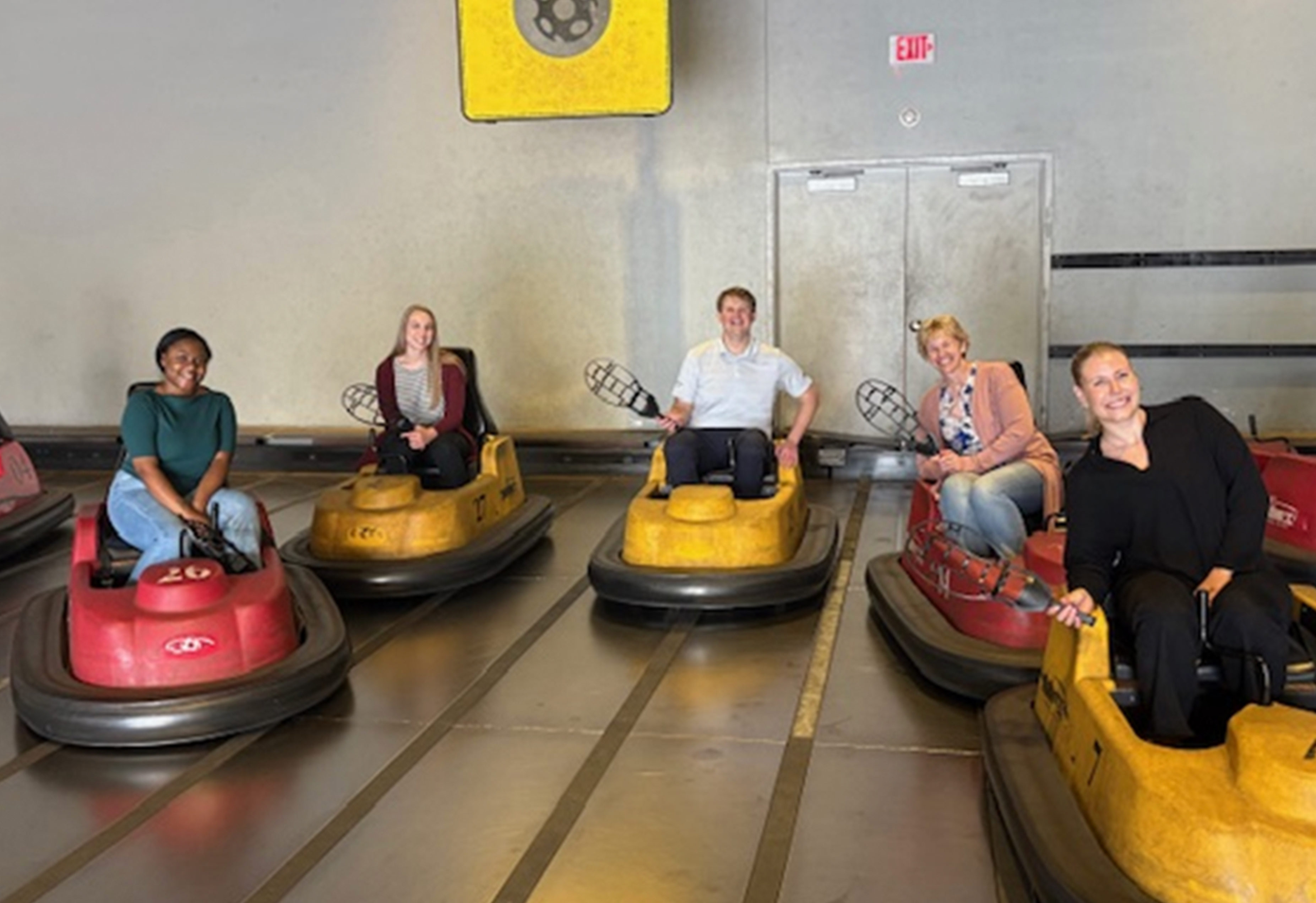 A group of trainees standing at a wirly ball team building event.